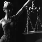 A close-up black and white photo of the Lady Justice figurine with scales.