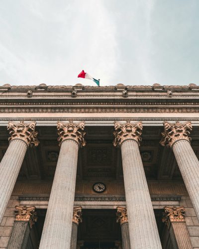 Low-angle view of a historic courthouse with columns and French flag in Lyon, France.