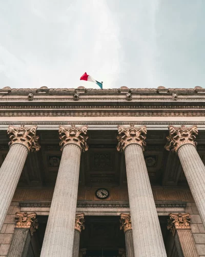 Low-angle view of a historic courthouse with columns and French flag in Lyon, France.