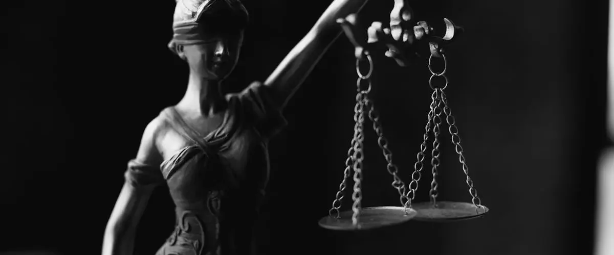 A close-up black and white photo of the Lady Justice figurine with scales.